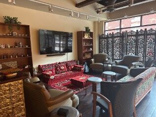 Main lounge area with chairs and couches and a television mounted on wall between two shelves